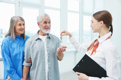 Photo of Smiling real estate agent with clipboard giving house key to new owner at home