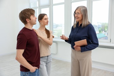 Photo of Smiling real estate agent with tablet working with couple at home