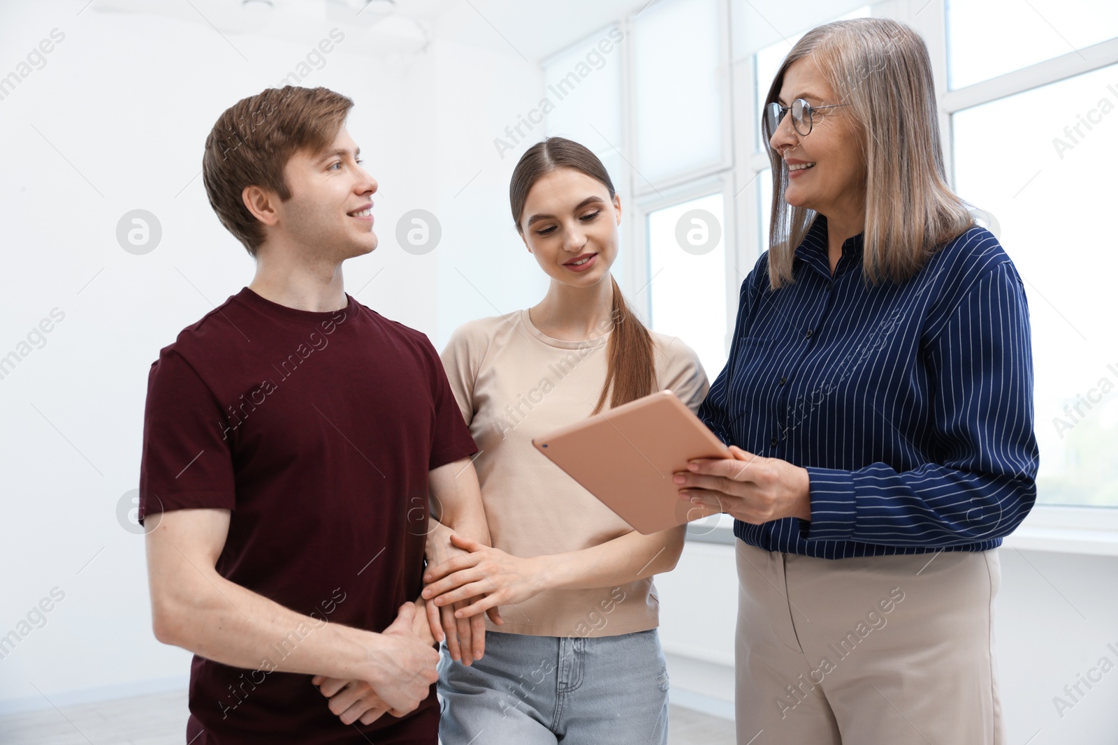 Smiling real estate agent with tablet working with couple at home Photo of Smiling real estate agent with tablet working with couple at home
