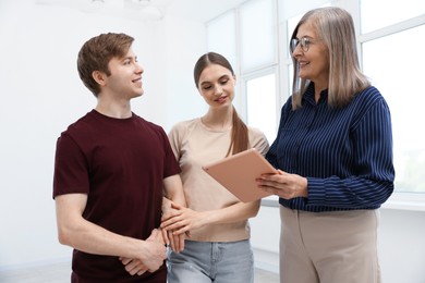 Photo of Smiling real estate agent with tablet working with couple at home