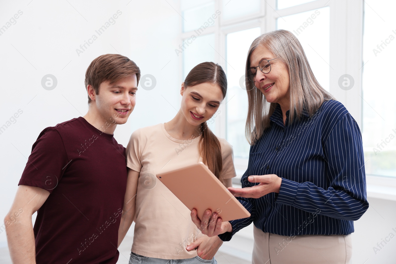 Smiling real estate agent with tablet working with couple at home Photo of Smiling real estate agent with tablet working with couple at home