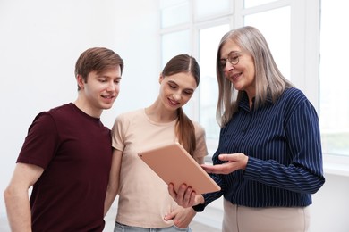 Photo of Smiling real estate agent with tablet working with couple at home