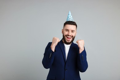 Photo of Happy Birthday. Handsome man with party hat on grey background