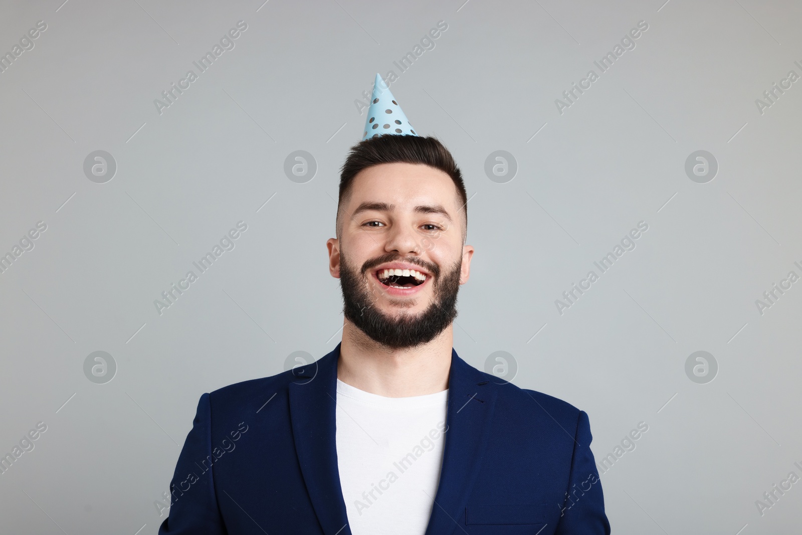 Happy Birthday. Handsome man with party hat on grey background Photo of Happy Birthday. Handsome man with party hat on grey background