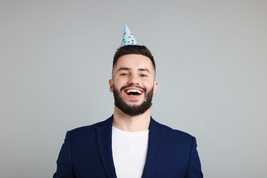 Photo of Happy Birthday. Handsome man with party hat on grey background