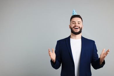 Photo of Happy Birthday. Handsome man with party hat on grey background, space for text
