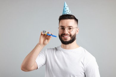 Photo of Happy Birthday. Handsome man with party hat and blower on grey background