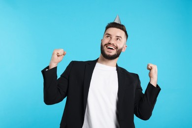 Photo of Happy Birthday. Handsome man with party hat on light blue background