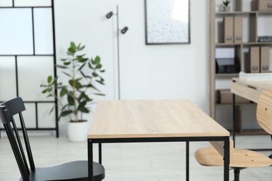 Photo of Wooden desk and chairs indoors, closeup. Office interior