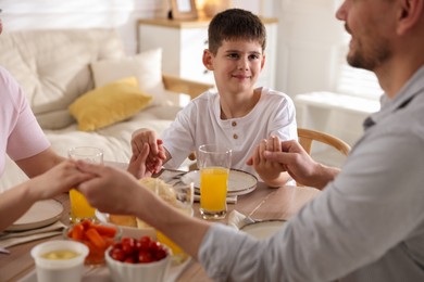 Photo of Family praying together before dinner at table indoors