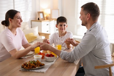 Photo of Family praying together before dinner at table indoors