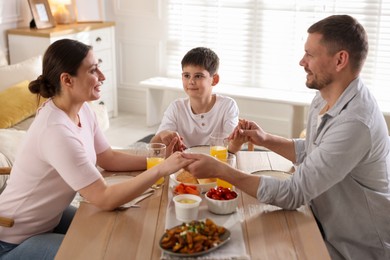 Photo of Family praying together before dinner at table indoors