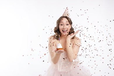 Photo of Birthday celebration. Woman with cupcake and confetti on white background