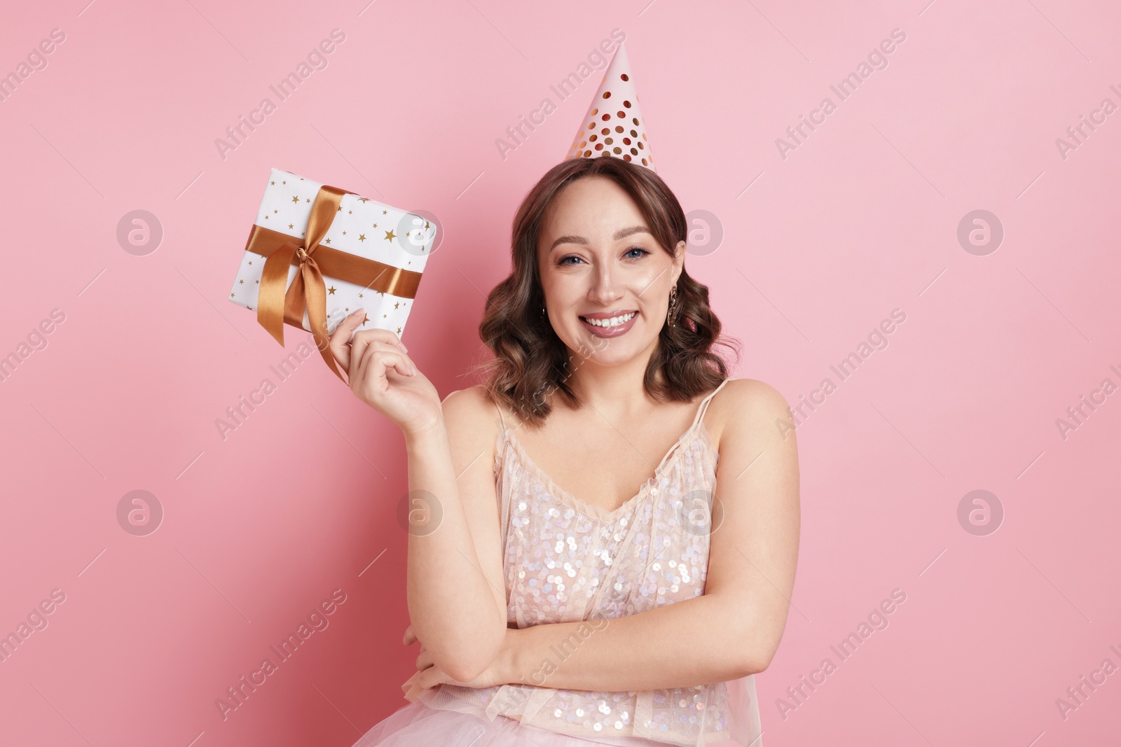 Birthday celebration. Woman with gift on pink background Photo of Birthday celebration. Woman with gift on pink background