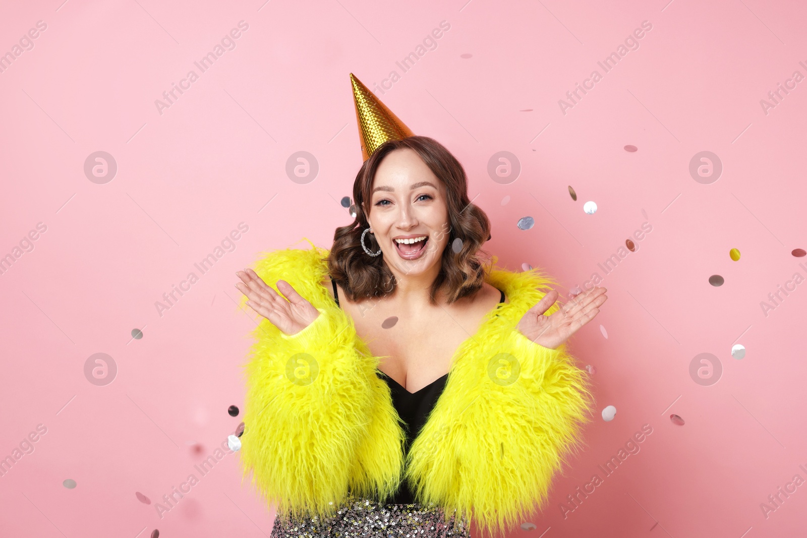 Birthday celebration. Woman on pink background with confetti Photo of Birthday celebration. Woman on pink background with confetti
