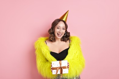 Photo of Birthday celebration. Woman with gift on pink background