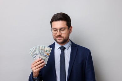 Photo of Greedy banker with dollar banknotes on grey background