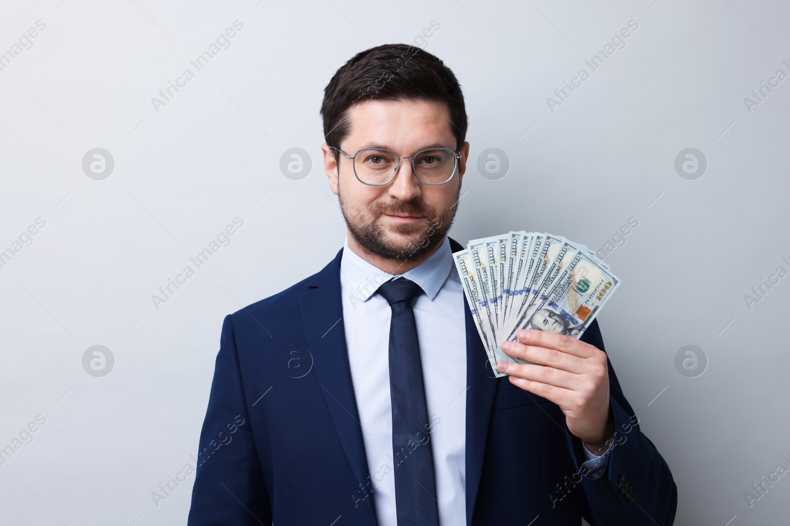 Greedy banker with dollar banknotes on grey background Photo of Greedy banker with dollar banknotes on grey background