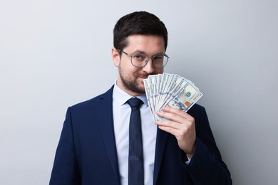 Photo of Greedy banker sniffing dollar banknotes on grey background