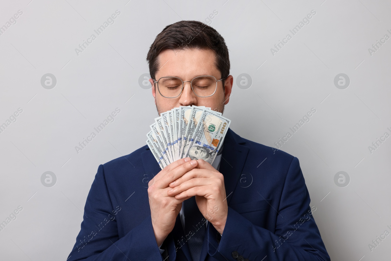 Greedy banker sniffing dollar banknotes on grey background Photo of Greedy banker sniffing dollar banknotes on grey background