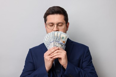Photo of Greedy banker sniffing dollar banknotes on grey background