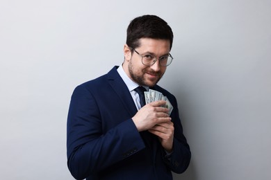 Photo of Greedy banker with dollar banknotes on grey background