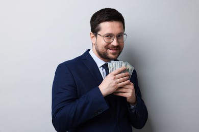 Photo of Greedy banker holding dollar banknotes and smiling on grey background