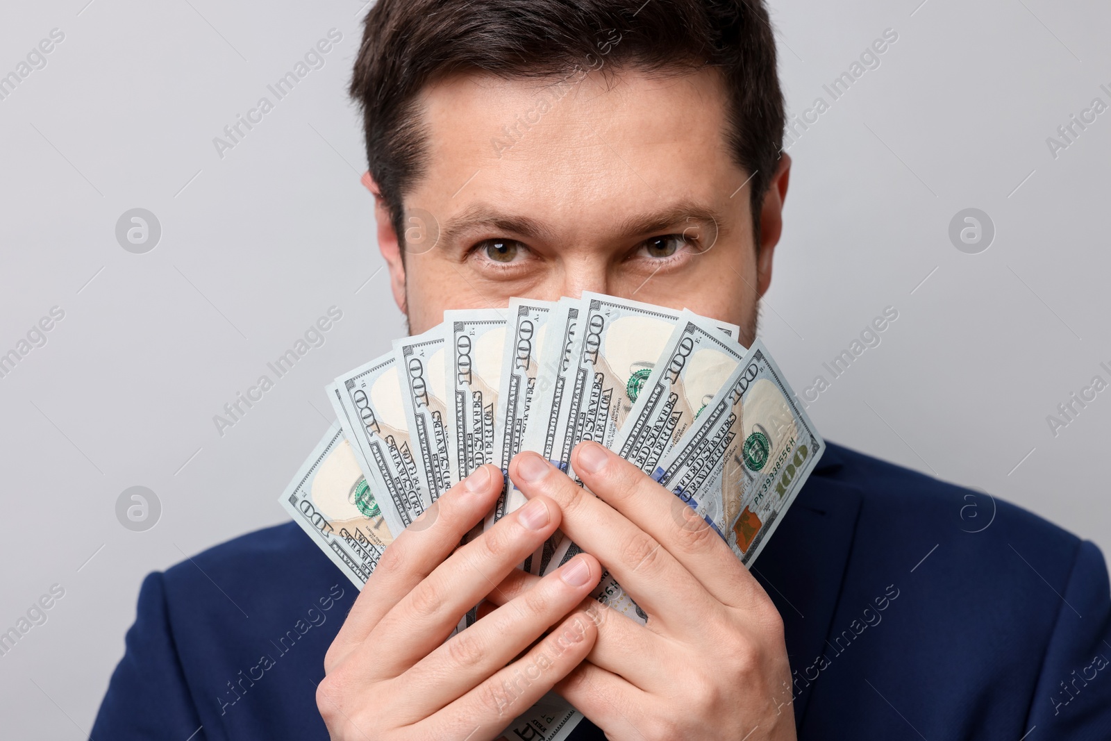Greedy banker with dollar banknotes on grey background, closeup Photo of Greedy banker with dollar banknotes on grey background, closeup