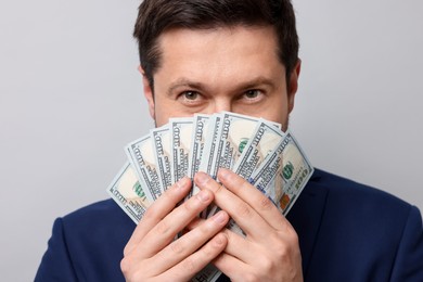 Photo of Greedy banker with dollar banknotes on grey background, closeup
