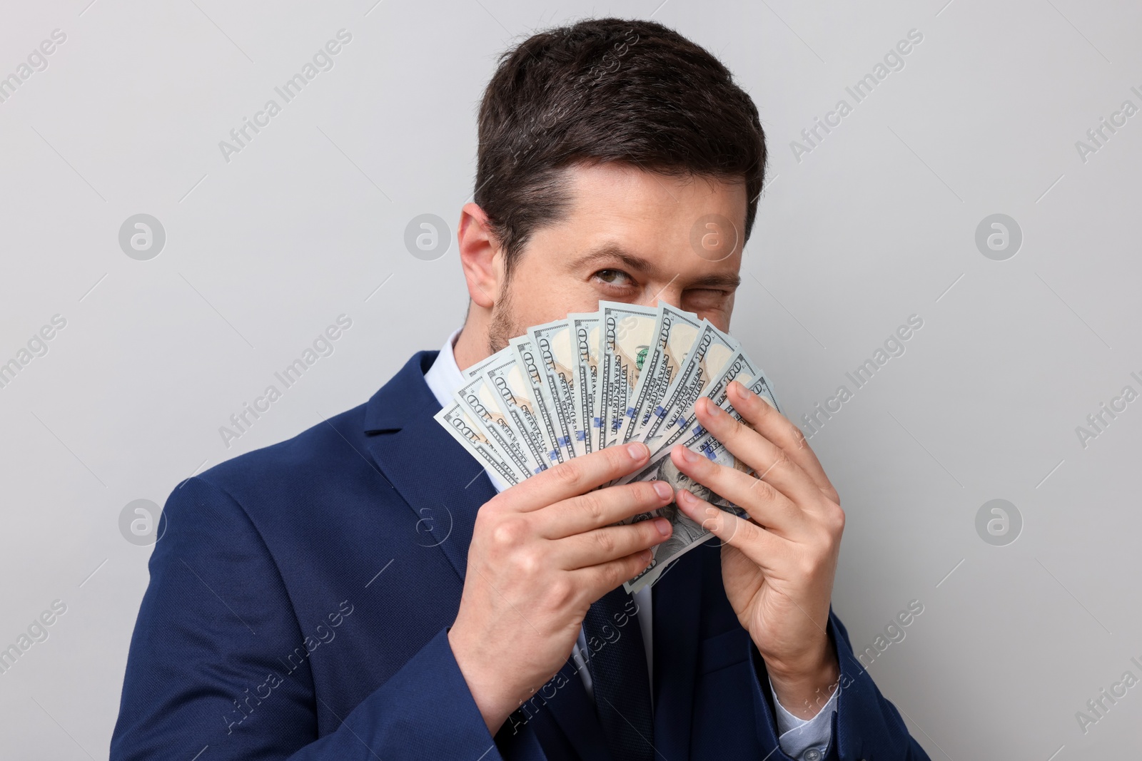 Greedy banker with dollar banknotes on grey background, closeup Photo of Greedy banker with dollar banknotes on grey background, closeup
