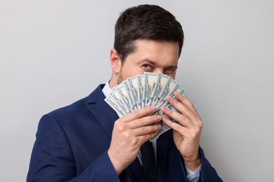 Photo of Greedy banker with dollar banknotes on grey background, closeup