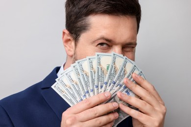Photo of Greedy banker with dollar banknotes on grey background, closeup