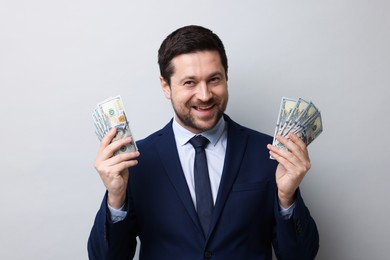 Photo of Greedy banker holding dollar banknotes and smiling on grey background