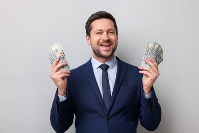 Photo of Greedy banker holding dollar banknotes and smiling on grey background
