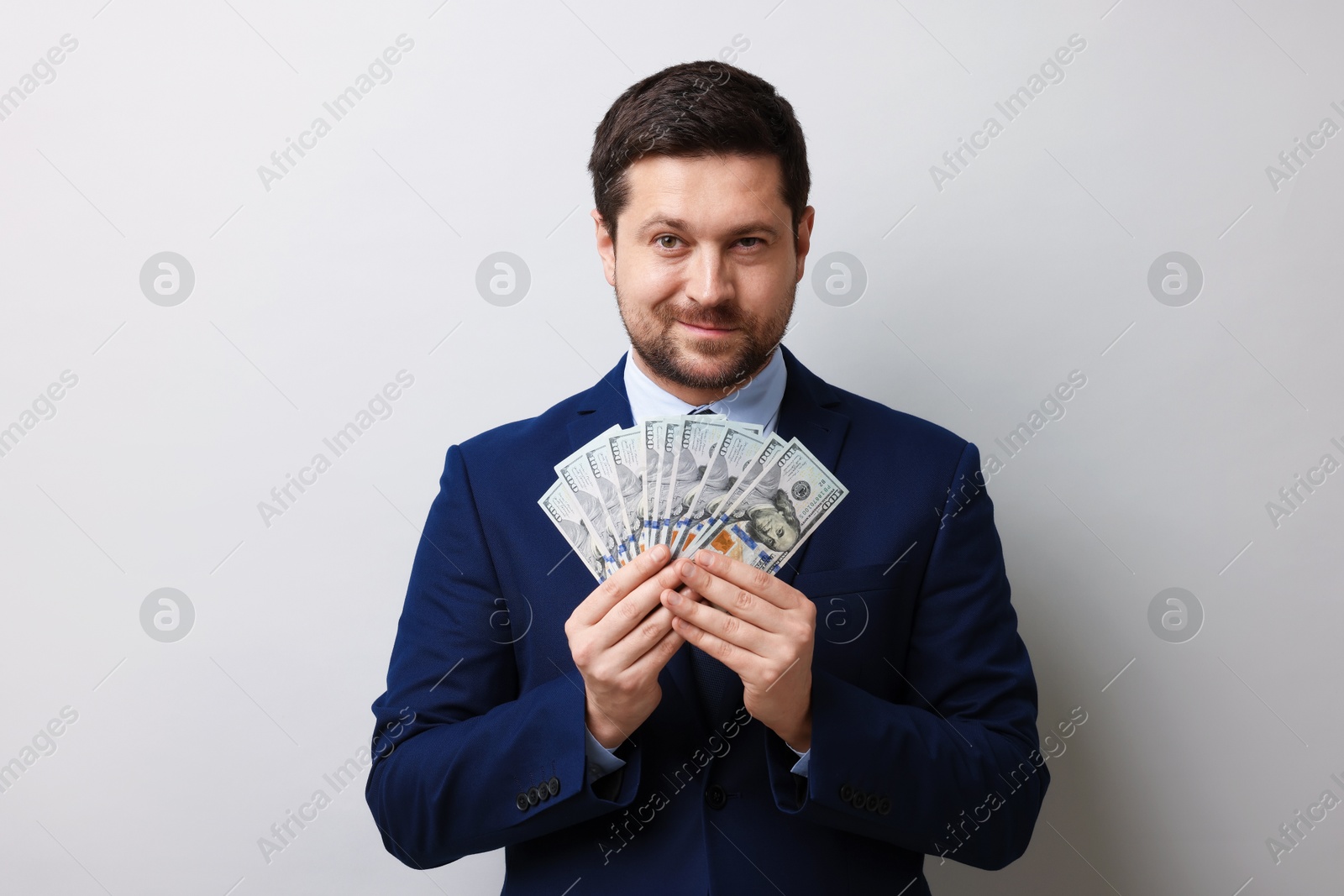 Greedy banker with dollar banknotes on grey background Photo of Greedy banker with dollar banknotes on grey background