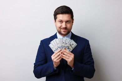 Photo of Greedy banker with dollar banknotes on grey background