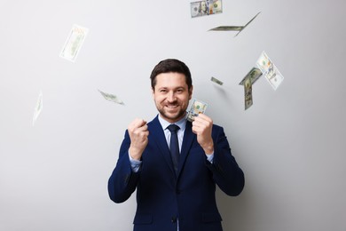 Photo of Happy greedy banker under money shower on grey background