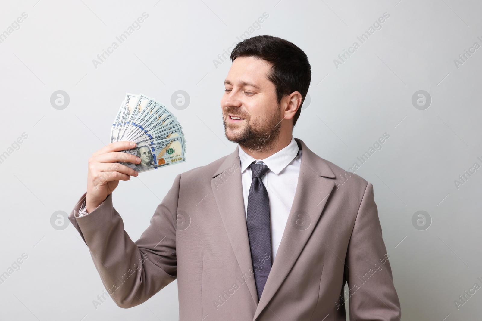 Happy greedy banker waving money on grey background Photo of Happy greedy banker waving money on grey background