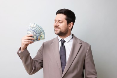 Photo of Happy greedy banker waving money on grey background