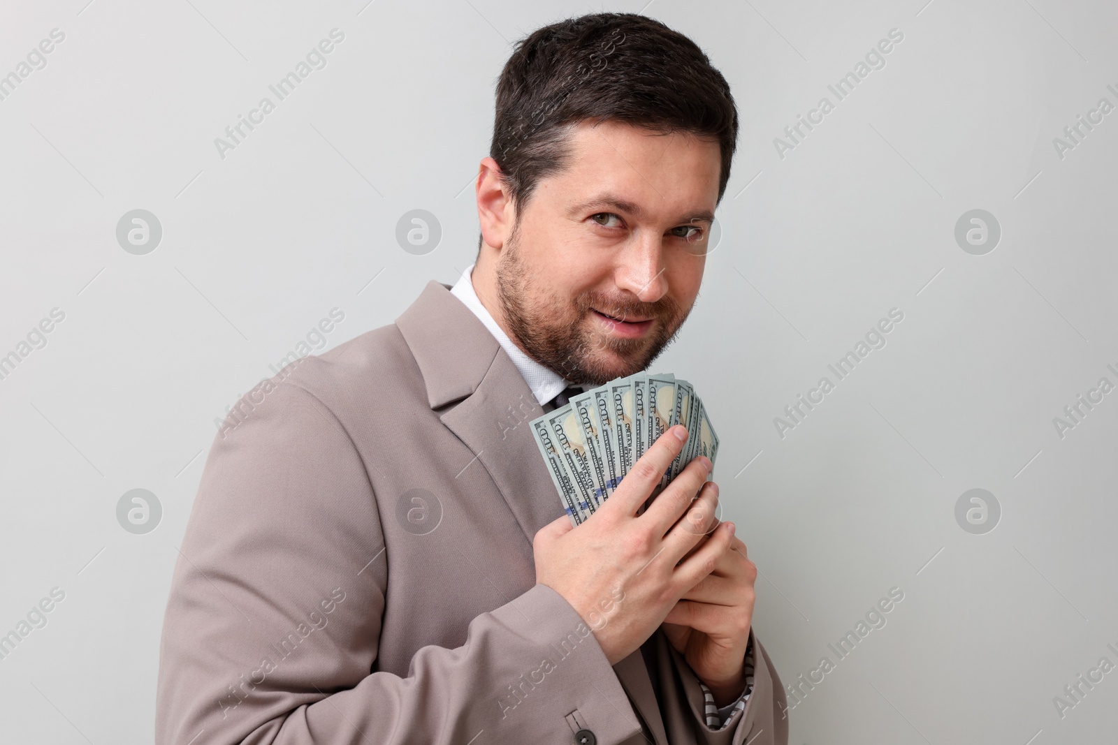 Greedy banker with dollar banknotes on grey background Photo of Greedy banker with dollar banknotes on grey background
