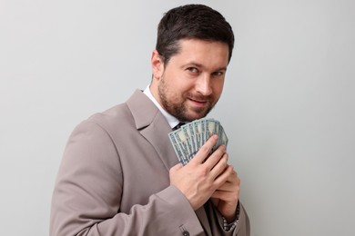 Photo of Greedy banker with dollar banknotes on grey background