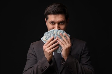 Photo of Greedy banker with dollar banknotes on black background