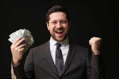 Photo of Happy greedy banker with dollar banknotes on black background