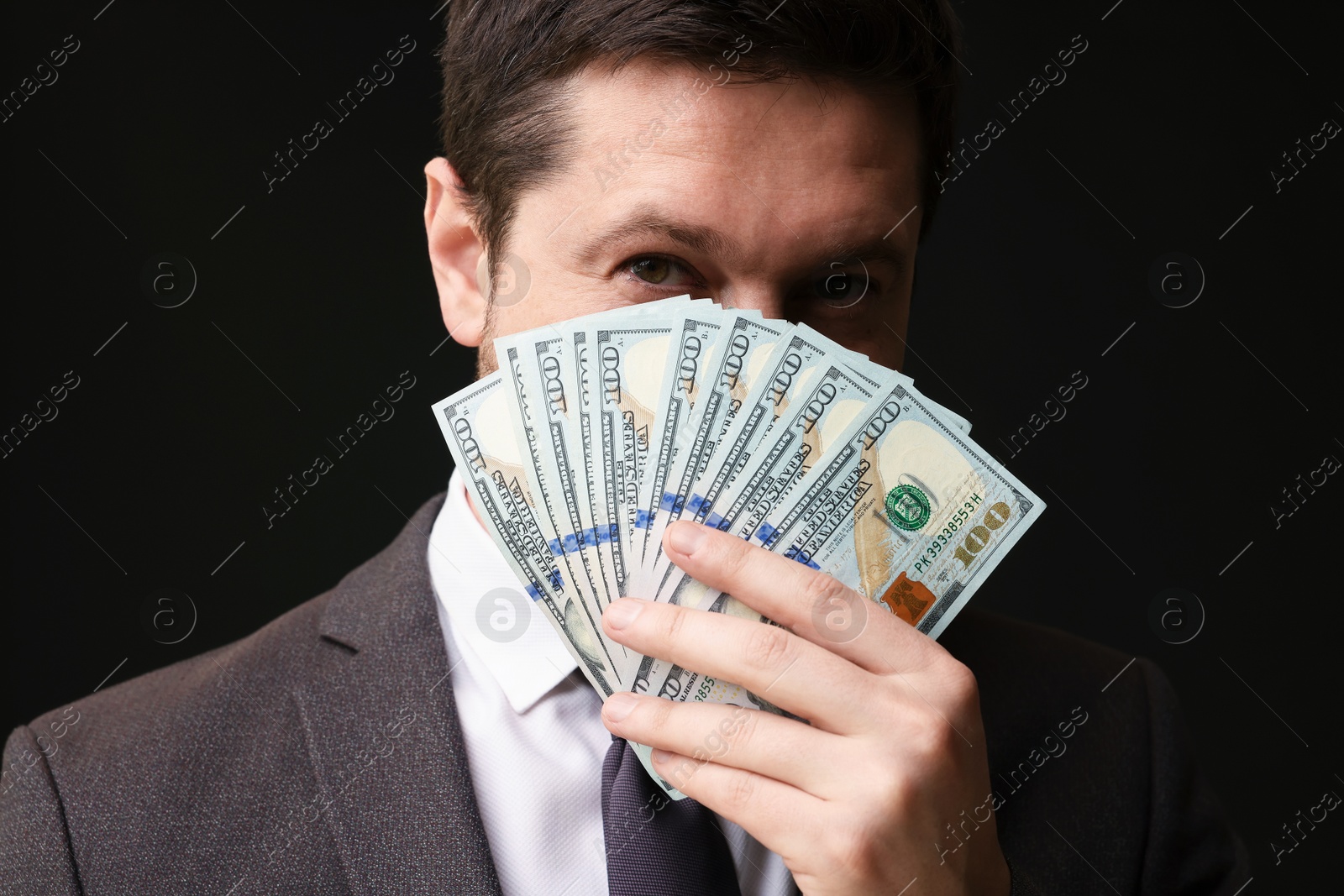 Greedy banker with dollar banknotes on black background, closeup Photo of Greedy banker with dollar banknotes on black background, closeup