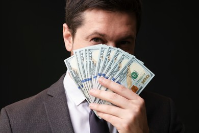 Photo of Greedy banker with dollar banknotes on black background, closeup