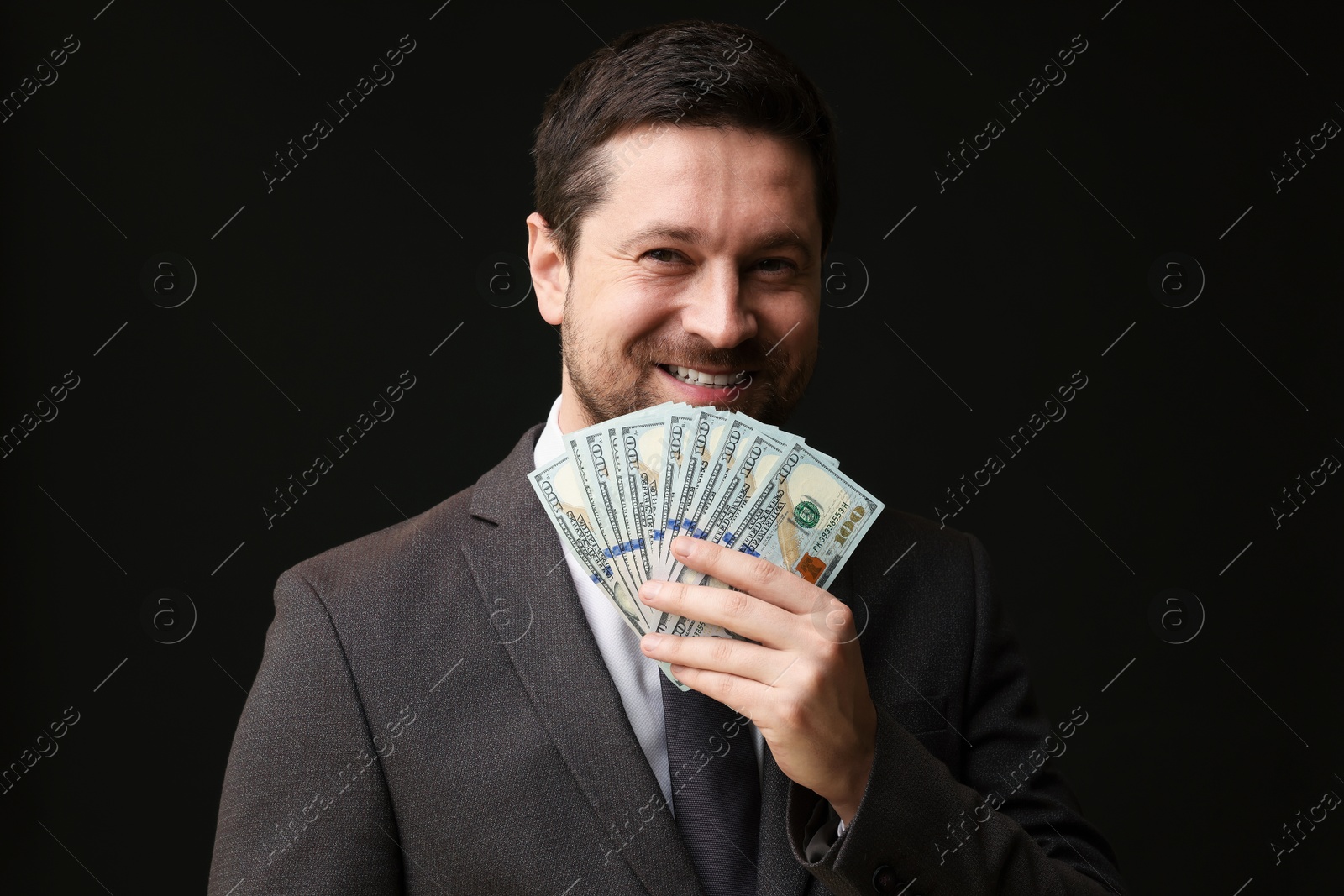 Happy greedy banker with dollar banknotes on black background Photo of Happy greedy banker with dollar banknotes on black background