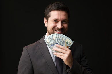 Photo of Happy greedy banker with dollar banknotes on black background