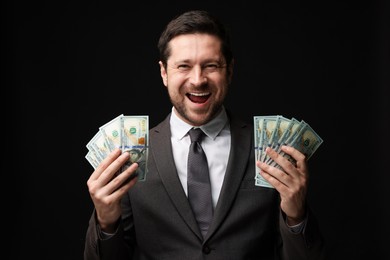 Photo of Happy greedy banker with dollar banknotes on black background
