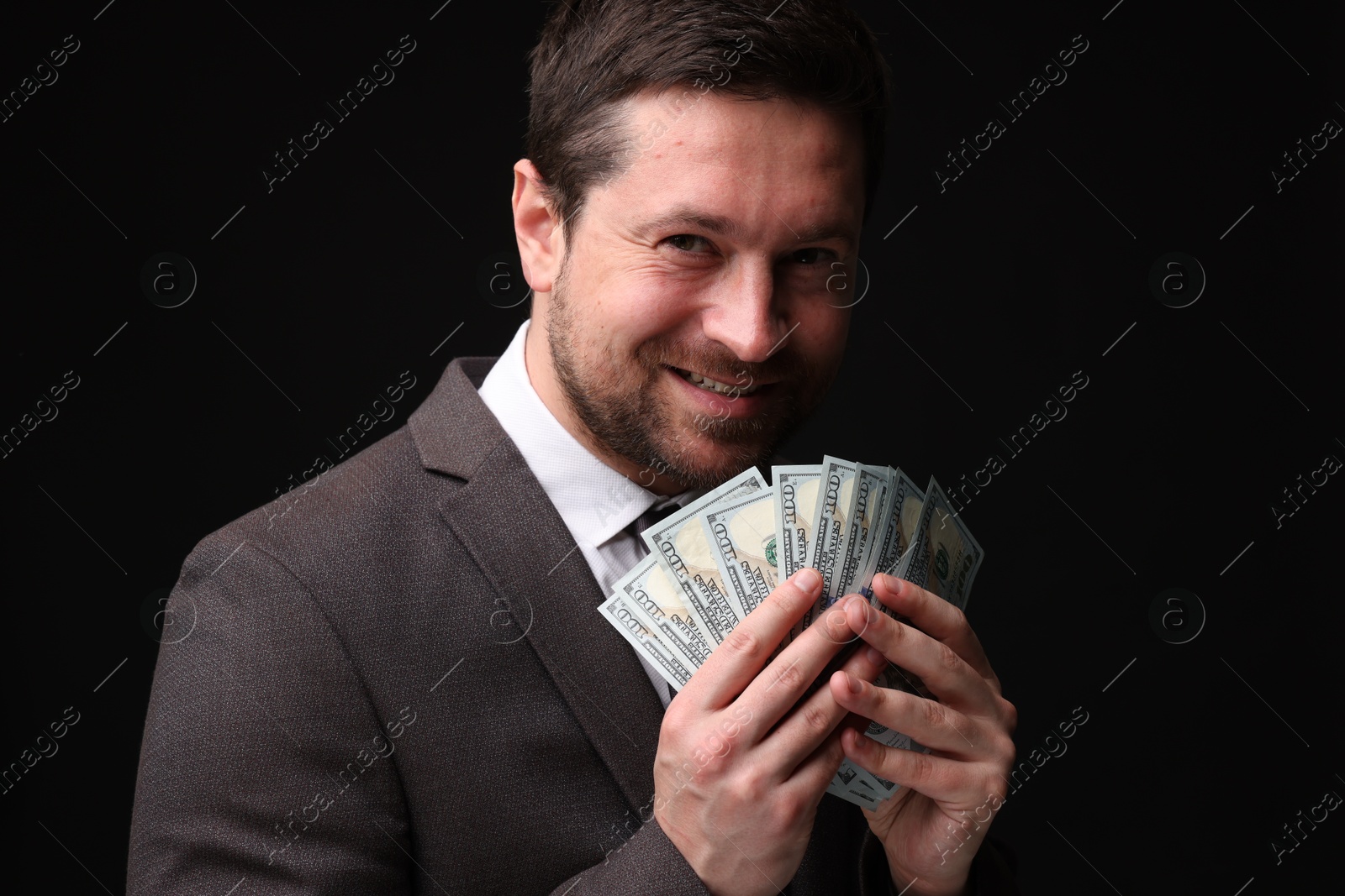 Happy greedy banker with dollar banknotes on black background Photo of Happy greedy banker with dollar banknotes on black background