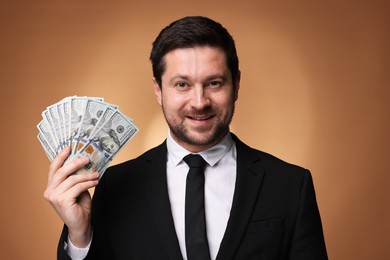 Photo of Happy greedy banker with dollar banknotes on golden background